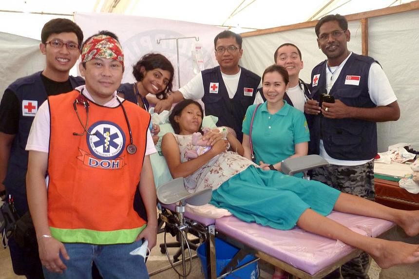 Dr Meera Ravindran (third from left), a medical officer with the Singapore General Hospital’s department of renal medicine, with the mother of a baby boy that she helped delivered when she volunteered to help earthquake victims in Bohol, Philippine