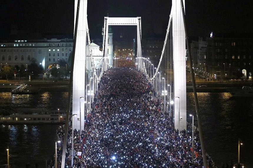 Tens of thousands of Hungarians hold up their mobile phones as they march across the Elisabeth Bridge during a protest against new tax on Internet data transfers in centre of Budapest, on Oct 28, 2014.&nbsp;Hungary will shelve plans to introduce a ta