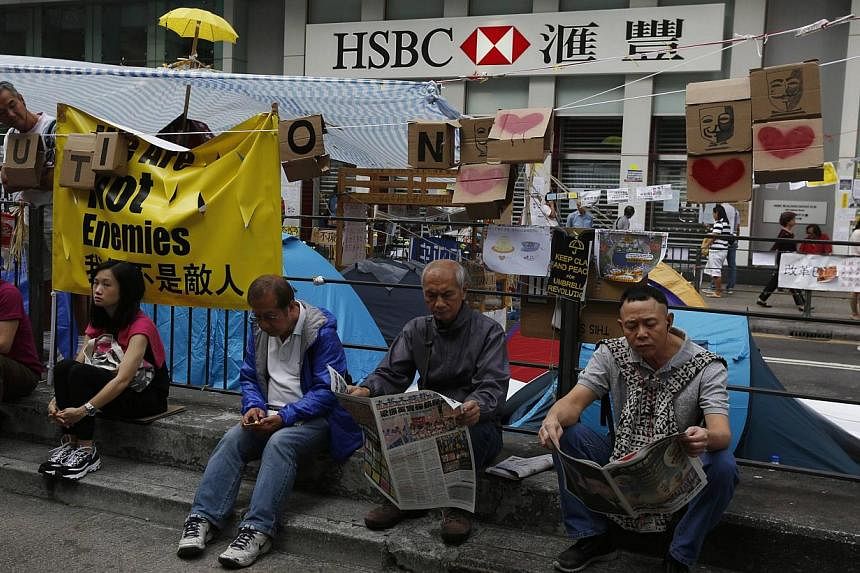 People reading newspapers outside an HSBC branch closed since the start of an Occupy movement at Mongkok shopping district in Hong Kong on Oct 16, 2014. Thousands have signed an online petition denouncing reported comments by HSBC Holdings board memb