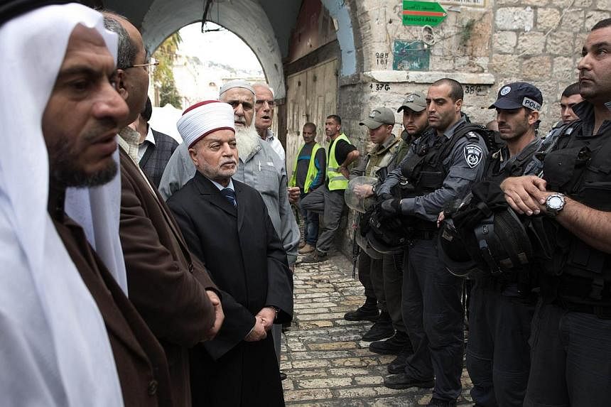 Israeli border policemen prevent the Mufti of Jerusalem Mohammed Hussein (centre) from entering the Al-Aqsa mosque compound in the old city of Jerusalem on Oct 30, 2014 after Israeli authorities temporarily closed the compound, Islam's third holiest 
