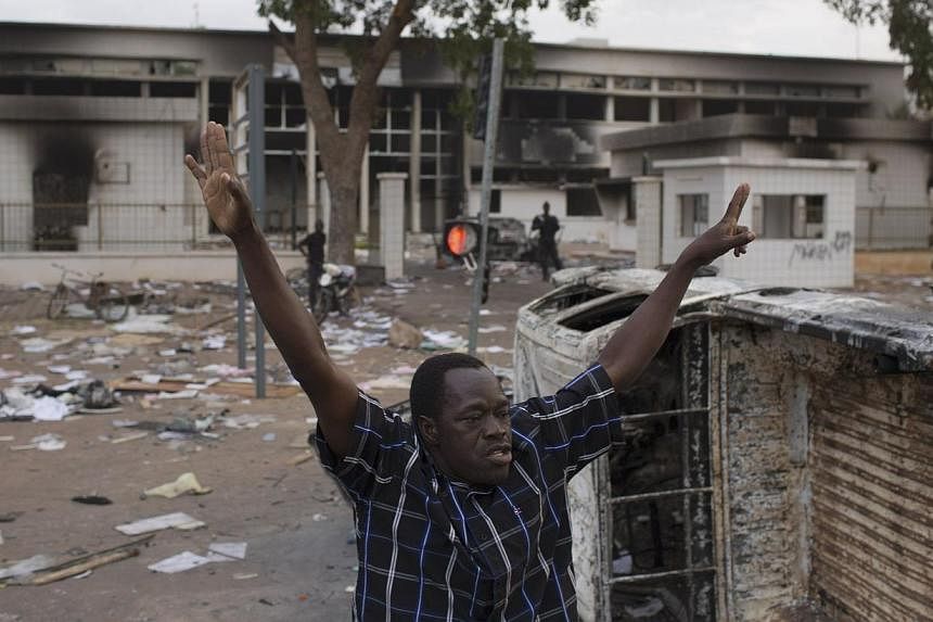 A man celebrates the departure of ex-President Blaise Compaore in front of the burned parliament building in Ouagadougou, capital of Burkina Faso, Oct 31, 2014.&nbsp;Burkina Faso prepared for another day of mass protests on Sunday as opposition and c