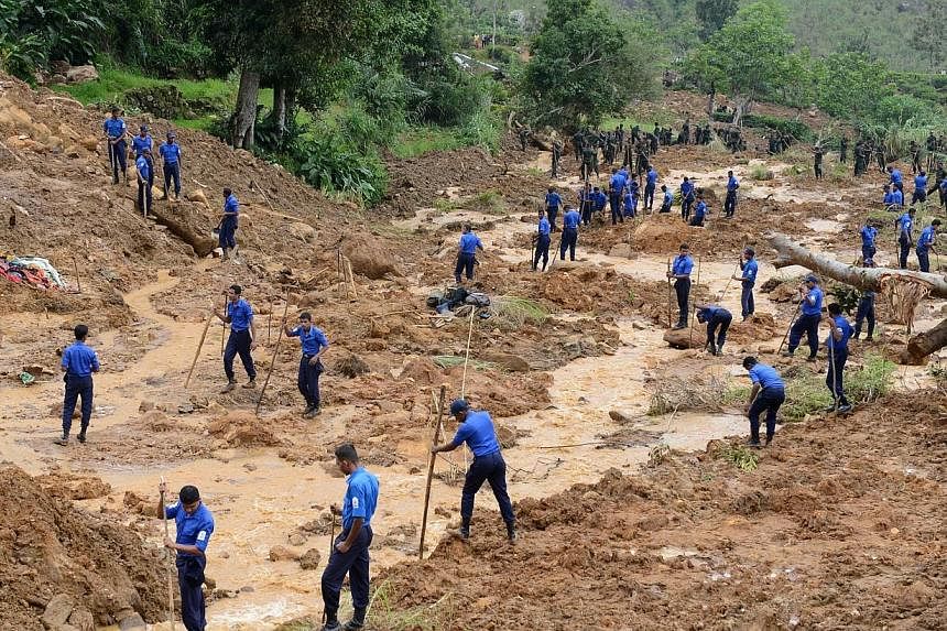 Sri Lankan military personel use poles and hoes during a search operation at the site of a landslide caused by heavy monsoon rains in Koslanda village in central Sri Lanka on Nov 1, 2014.&nbsp;Heavy rains slowed the search for victims of a major muds