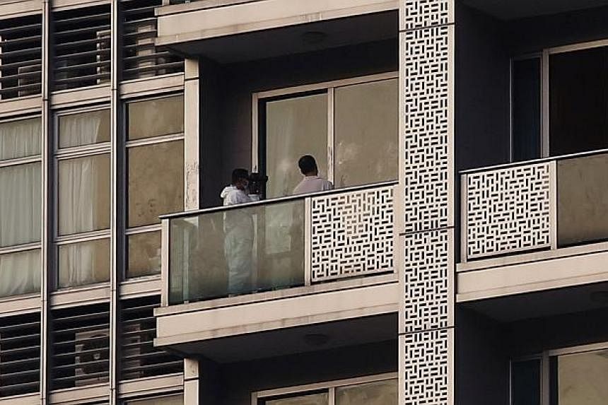A policeman takes a photo on the balcony of a unit in which two women's bodies were found in a flat at Hong Kong's Wan Chai district Nov 1, 2014. A Bank of America Merrill Lynch employee was arrested in Hong Kong on Saturday in connection with the su