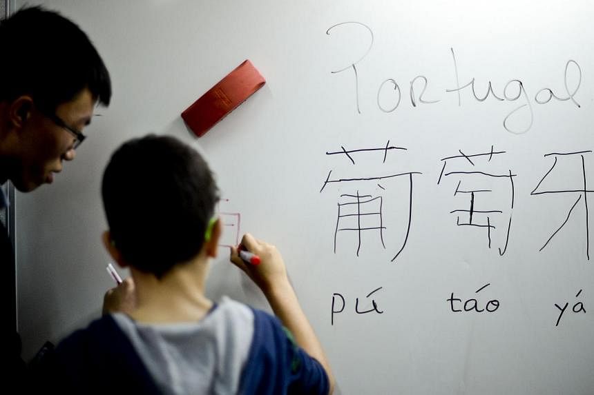Professor Wang Xin Liang checks a pupil's writing on a board during a Chinese class at Parque School in Sao Joao da Madeira on Oct 13, 2014.-- PHOTO: AFP