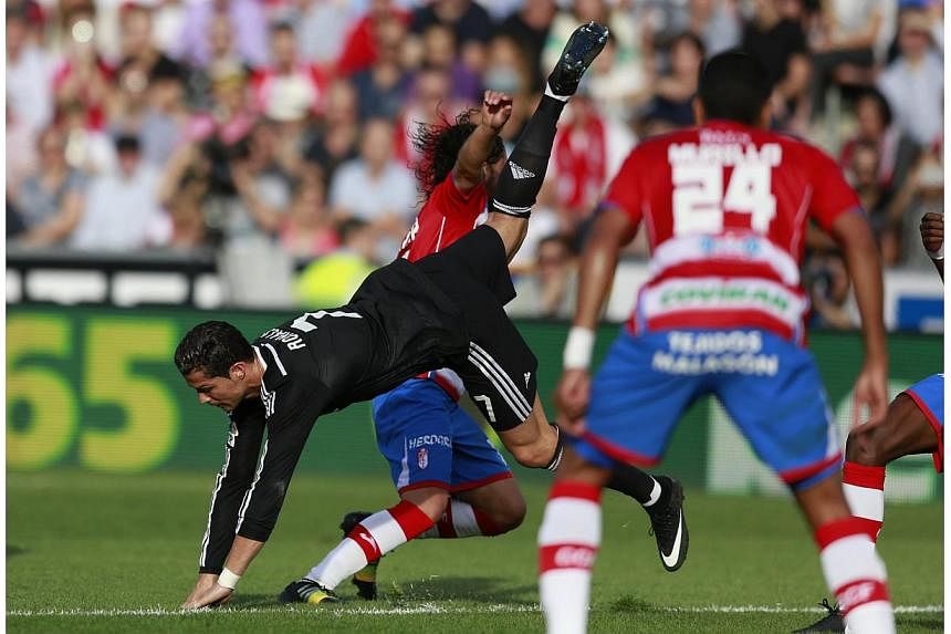 Real Madrid's Cristiano Ronaldo is tackled by Manuel Iturra during their Spanish First Division soccer match at Nuevo Los Carmenes stadium in Granada, Nov 1, 2014. &nbsp;Real Madrid moved to the top of La Liga for the first time this season as goals 