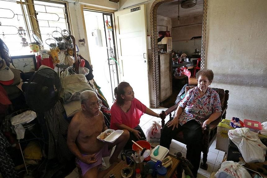 Madam Noriza A. Mansor (in pink) looks on as Mr Tan Soy Yong (left), 76, eats the chicken rice that she bought for Mr Tan and his wife Lee Bee Yian&nbsp;in their 2-room HDB Potong Pasir flat. -- PHOTO: ST FILE