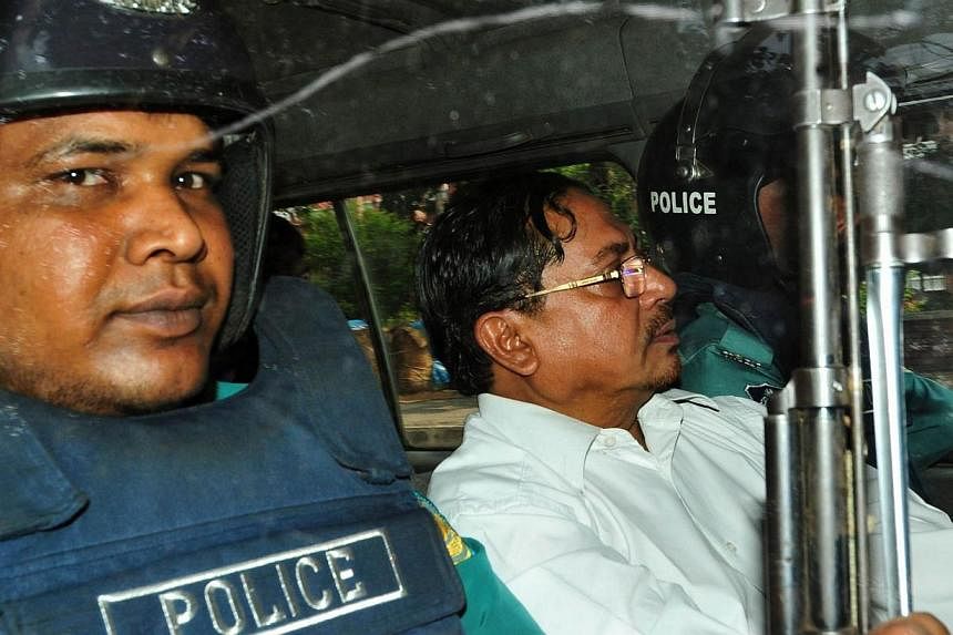 In this photograph taken on May 9, 2013, Bangladeshi Jamaat-e-Islami leader, Mohammad Kamaruzzaman, (right) sits next to a police officer as he leaves court in Dhaka.&nbsp;Violence broke out in Bangladesh on Monday after the country's highest court u