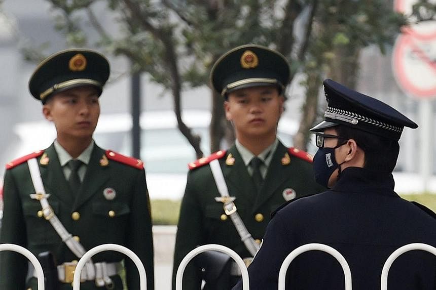 A Chinese police officer (right) stands guard with paramilitary police officers on a sidewalk in central Beijing on Oct 20, 2014, on the day the Communist Party opened a major plenum meeting.&nbsp;China has passed an anti-espionage law that could wid