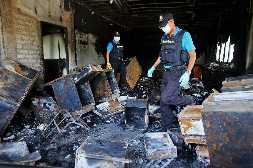 Thai forensic police inspect the burnt remains of the district government bureau after it was allegedly set alight by Muslim militants in Pattani province on Oct 28, 2014.&nbsp;-- PHOTO: AFP
