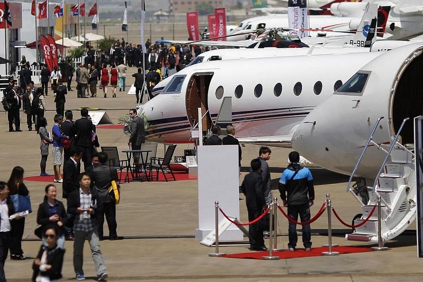 Guests walk next to aircraft during the Asian Business Aviation Conference and Exhibition (ABACE) at Hongqiao International Airport in Shanghai in this April 15, 2014. -- PHOTO: REUTERS