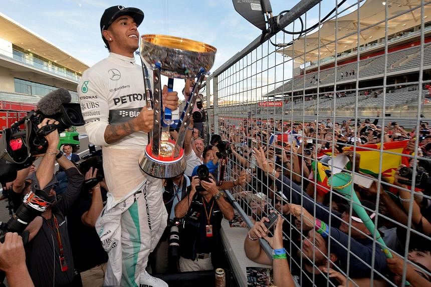 Mercedes AMG Petronas driver Lewis Hamilton of Britain celebrates with fans after winning the United States Formula One Grand Prix at the Circuit of The Americas in Austin, Texas on Nov 2, 2014. -- PHOTO: AFP