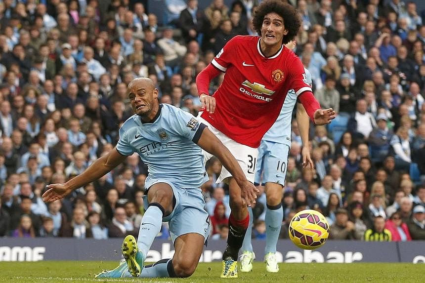Manchester City's Vincent Kompany (left) falls in front of Manchester United's Marouane Fellaini during their English Premier League match at the Etihad Stadium in Manchester on Nov 2, 2014. -- PHOTO: REUTERS