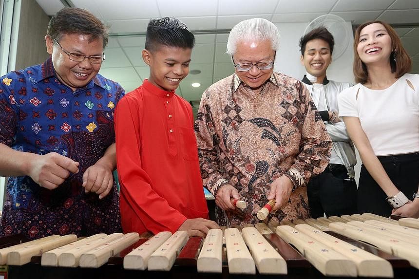 (From left) Music instructor Budi Hartiana, and Ain beneficiary Zainul Aladdin Azfar giving President Tony Tan Keng Yam a quick lesson on the musical instrument kolintang. With them are 98.7FM DJs Joachim Gomez and Sonia Chew. -- ST PHOTO: SEAH KWANG