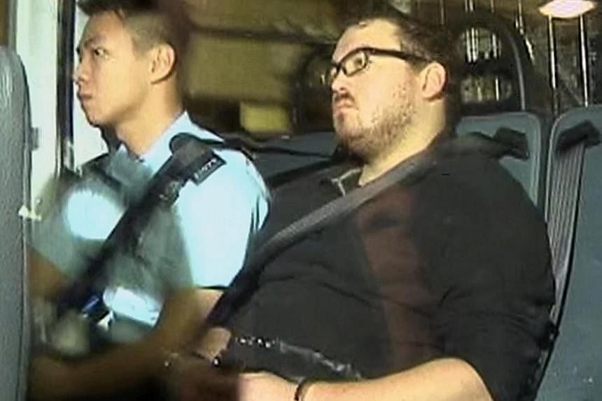 Rurik Jutting (right), a 29-year-old British banker who has been charged with two counts of murder, sits in a police van as it arrives at a court in Hong Kong in this video still. -- PHOTO: REUTERS