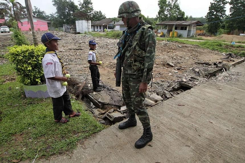 A soldier speaks with students at a school in Pattani province, south of Bangkok on Nov 3, 2014.&nbsp;The Thai authorities have distributed hundreds of assault rifles to village volunteers in the insurgency-battered south, in a move seemingly at odds