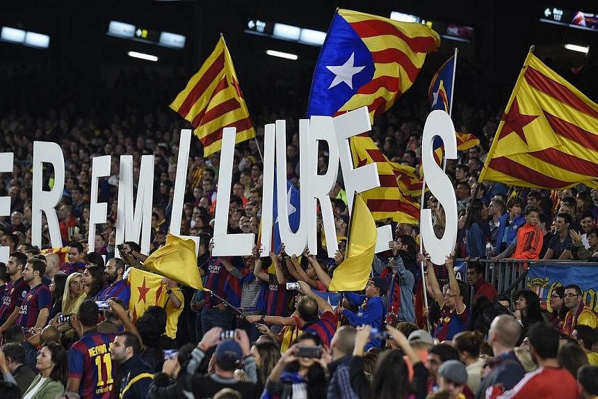 Chong Zi Liang/SPH: Barcelona Football Club supporters holding up placards that say "we are free" and waving Catalan flags during Barcelona's clash with Celta Vigo at the Camp Nou on Nov 1, 2014. -- PHOTO: AFP