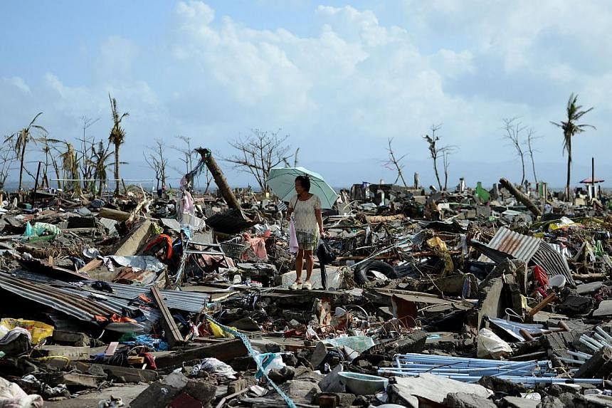A person walks among the debris of houses destroyed by Super Typhoon Haiyan in Tacloban in the eastern Philippine island of Leyte. -- PHOTO: AFP&nbsp;