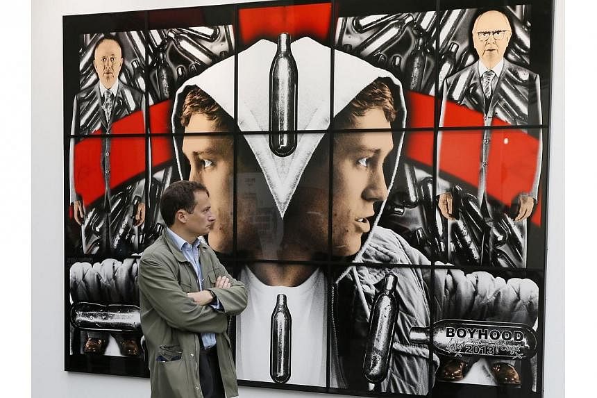 A man watches "Boyhood", a 2013 mixed media piece by artists Gilbert and George during the press opening of the Foire Internationale d'Art Contemporain (FIAC, International Contemporary Art Fair) at the Grand Palais on Oct 22, 2014 in Paris. -- PHOTO