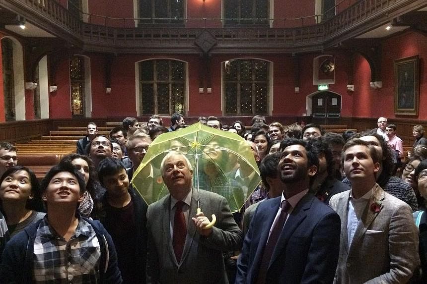 Hong Kong's last British governor Chris Patten, holds a yellow umbrella -- a symbol of the Occupy movement in Hong Kong -- after it was given to him by a University of Oxford student in the audience during an event at the Oxford Union in Oxford on Oc