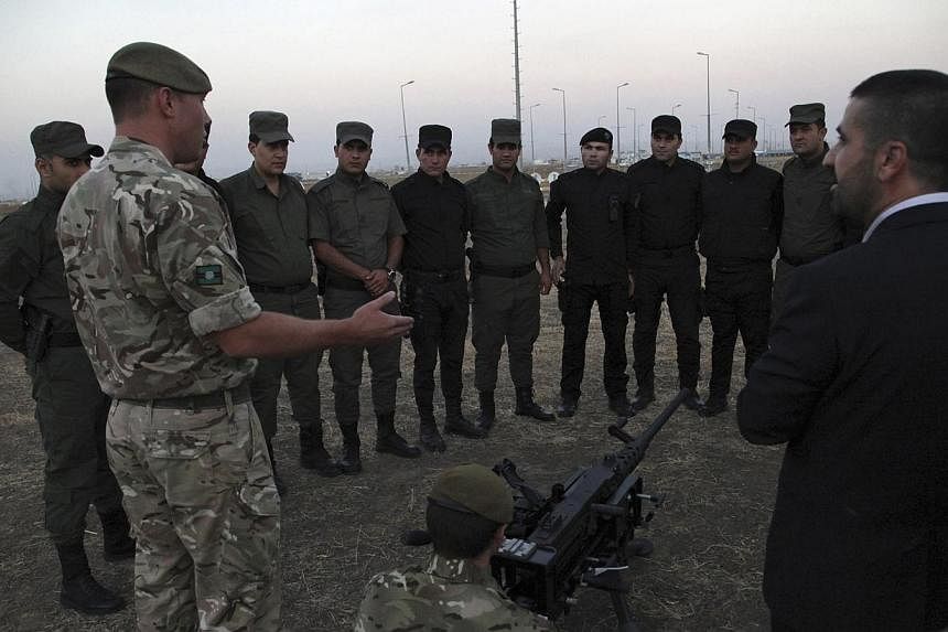 British soldiers train Kurdish Peshmerga fighters on how to use a heavy machine gun in Arbil, the capital of the autonomous Kurdish region of northern Iraq on Oct 13, 2014.&nbsp;Britain will boost the number of its army trainers in Iraq in the coming