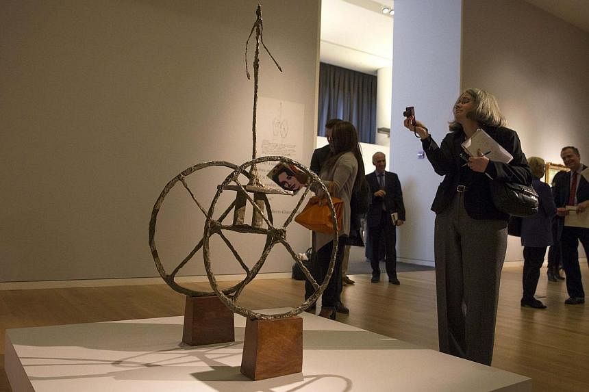A woman takes a photo of 'Chariot', a rare 1950 bronze sculpture by Swiss artist Alberto Giacometti. -- PHOTO: REUTERS