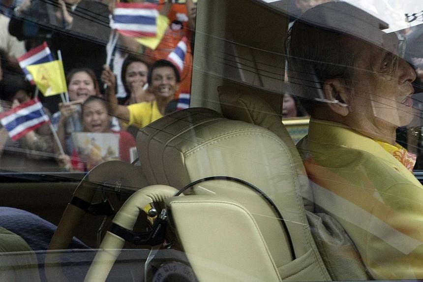 Well-wishers wave flags and pray as Thailand's King Bhumibol Adulyadej leaves Siriraj hospital in Bangkok on Sept 15. 2014.&nbsp;Thailand's King Bhumibol Adulyadej, the world's longest-reigning monarch, has been treated for a swollen intestine and re