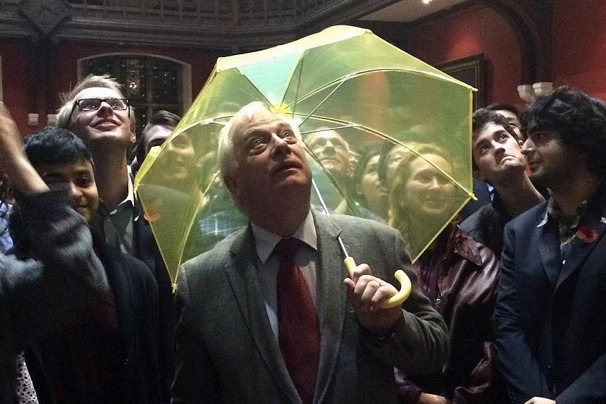 Hong Kong's last British governor Chris Patten holds a yellow umbrella - a symbol of the Occupy movement in Hong Kong - in this Oct 31 photo, after it was given to him by a University of Oxford student in the audience during an event at the Oxford Un