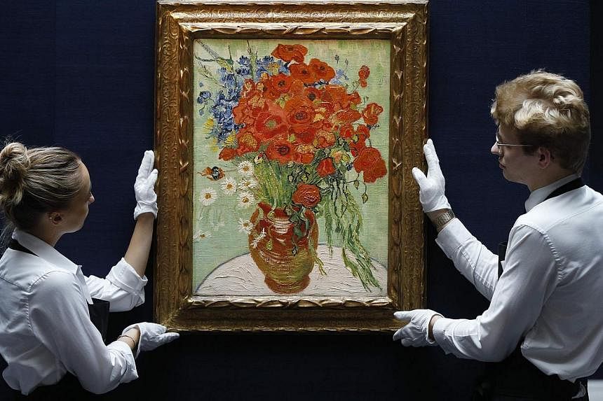 Two staff members pose in a gallery with Still Life, Vase with Daisies, and Poppies by Vincent Van Gogh from 1890 at Sotheby's auction house in London In October. -- PHOTO: REUTERS