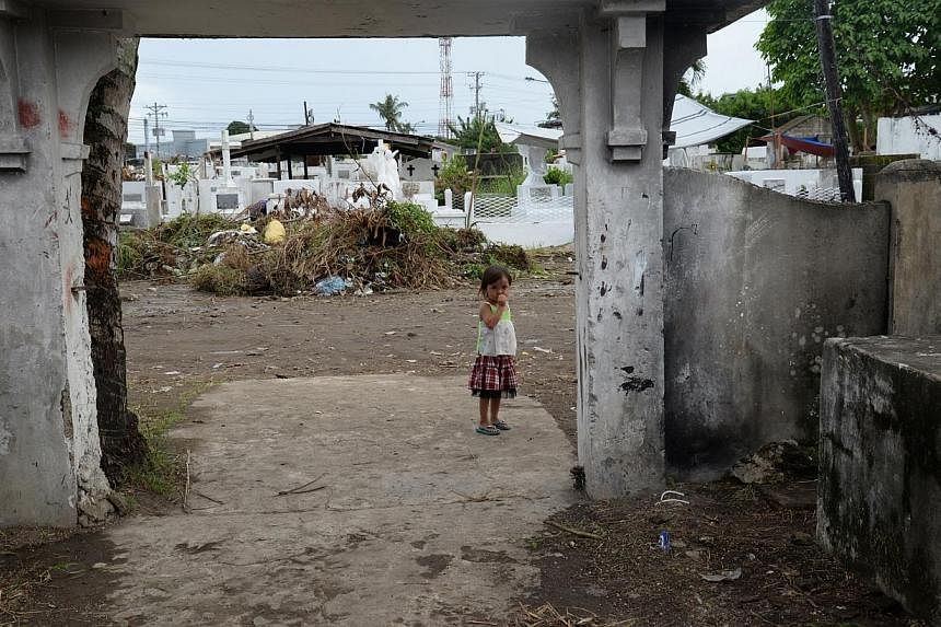 A young girl stands at the threshold of one of the gateways of a public cemetery in Tacloban city on the even of All Soul's Day - a religious holiday in the Philippines for remembering the dead every Oct 31. -- ST PHOTO:&nbsp;RAUL CAPUNPON DANCEL