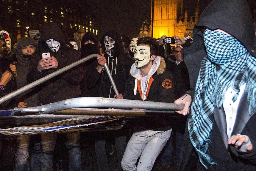 Anti-capitalist protesters wearing Guy Fawkes masks remove police barrickades during the Million Masks March in Parliament Square in London on November 5, 2014. -- PHOTO: AFP