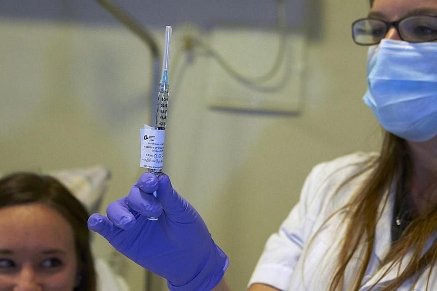 A nurse prepares a syringe containing an experimental Ebola virus vaccine next to a volunteer called Marie (left) during a media visit at the Lausanne University Hospital (CHUV) in Lausanne on Nov 4, 2014.&nbsp;The Europe Union and drugmakers pledged