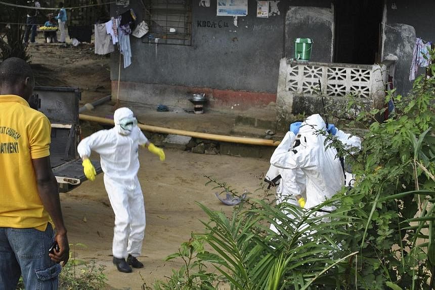Medical staff wearing protective suits gather at a health facility near the Liberia-Sierra Leone border in western Liberia on Nov 5, 2014.&nbsp;The number of Ebola cases is surging in Sierra Leone as the country suffers from a lack of treatment centr