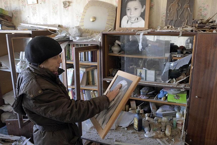 A woman looks at a portrait in her damaged apartment in a residential building following the recent shelling in Donetsk on Nov 5, 2014.&nbsp;Ukraine's tattered ceasefire came under new strain on Wednesday as shelling killed two teenagers playing foot