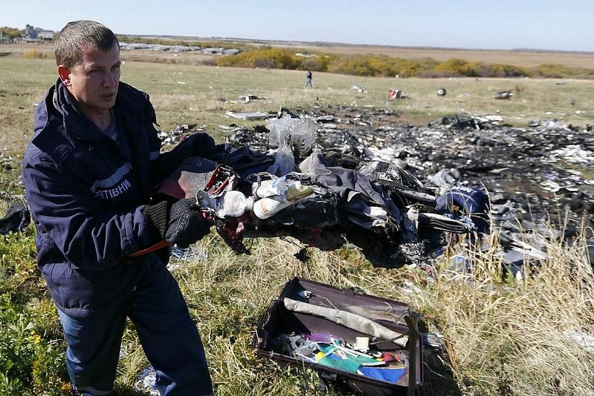 An Emergencies Ministry member walks near belongings and wreckage at the site where downed Malaysia Airlines Flight MH17 crashed, in the Donetsk region of Ukraine on Oct 13, 2014.&nbsp;Dutch investigators expect to begin recovering wreckage from the 