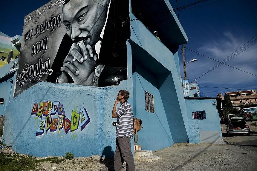 A tourist stands in front of a Martin Luther King graffiti in the Cova da Moura neighborhood of Amadora on the outskirts of Lisbon. One of the most ill reputed suburban neighborhoods of Europe, it is often likened to the favelas of Brazil and the tow