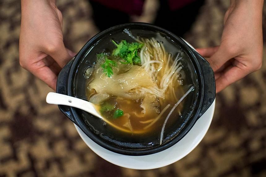 A waitress serving shark fin soup in a restaurant in Guangzhou, China. Hospitality groups Hilton Worldwide, Starwood Hotels and Resorts, and Hyatt are among major industry players here who have joined a campaign against serving the dish. -- PHOTO: AF