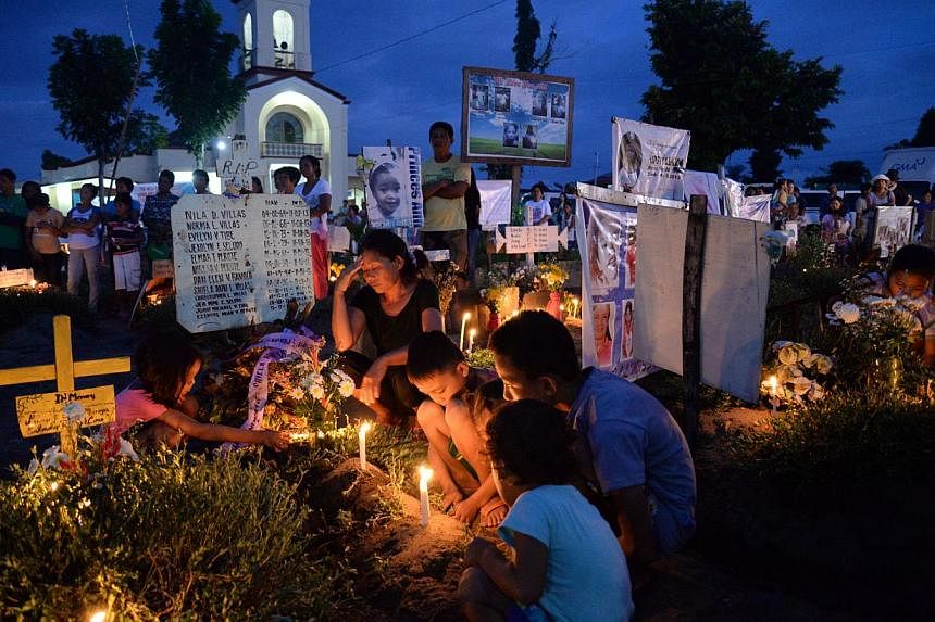 A family grieves for about a dozen kin on All Soul's Day, a religious holiday in the Philippines for remembering the dead every Oct 31, inside a makeshift cemetery at the front lawn of a church in San Joaquin village in Palo town, Leyte province. &nb