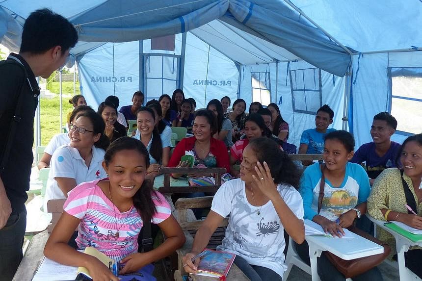 Filipino students taking lessons in a temporary school that was set up after Typhoon Haiyan damaged their original school in November 2013. - PHOTO: SINGAPORE RED CROSS