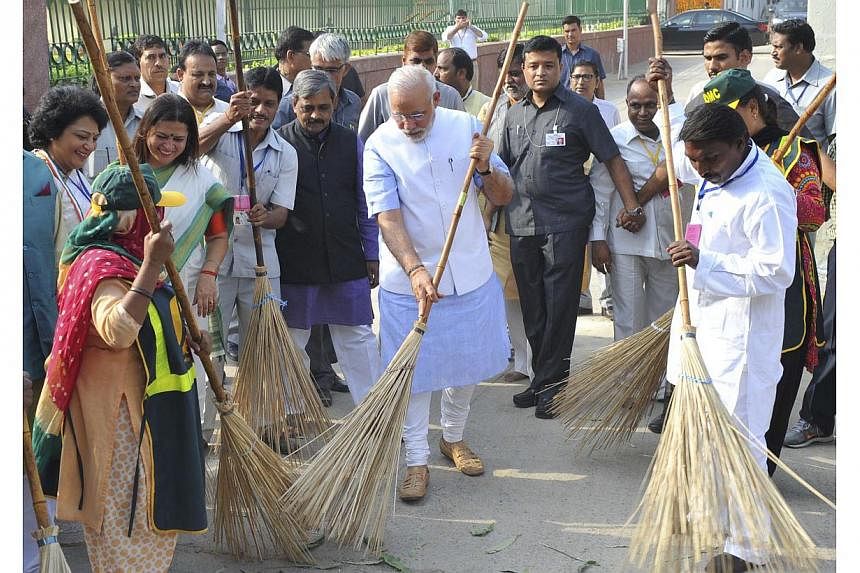 India's Prime Minister Narendra Modi (centre) cleans a road as he launches the Swachh Bharat Abhiyan, or Clean India Mission, in New Delhi in this Oct 2, 2014, picture provided by India's Press Information Bureau. -- PHOTO: REUTERS