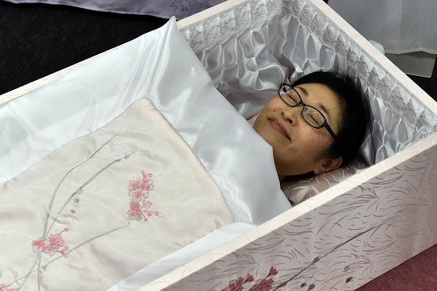 A woman lies in a coffin at the annual "Shukatsu Festa 2014" funeral business fair in Tokyo on August 24, 2014.