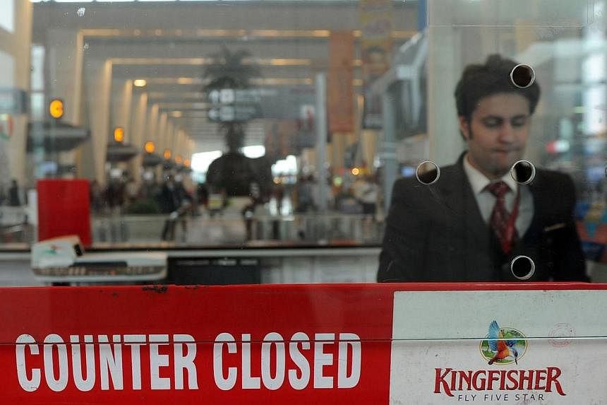 An Indian customer service representative stands inside the closed booth of a Kingfisher Airlines booking counter at Indira Gandhi International Airport in New Delhi on Oct 20, 2012.&nbsp;Shares of India's grounded Kingfisher Airlines face suspension