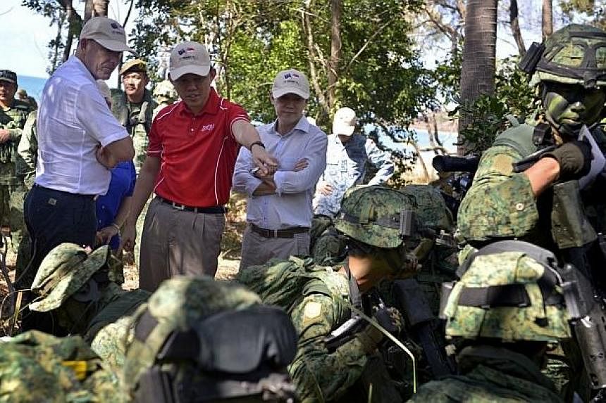 Second Minister for Defence Chan Chun Sing (centre, in red), Australian Assistant Minister for Defence Stuart Robert (left), and Chairman of the Government Parliamentary Committee for Defence and Foreign Affairs Lim Wee Kiak (right) observe troops fr