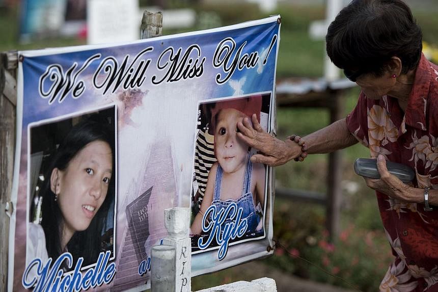 A relative visiting a grave in front of San Joaquin Church in Palo, near Tacloban, on Oct 15, 2014. -- PHOTO: AFP