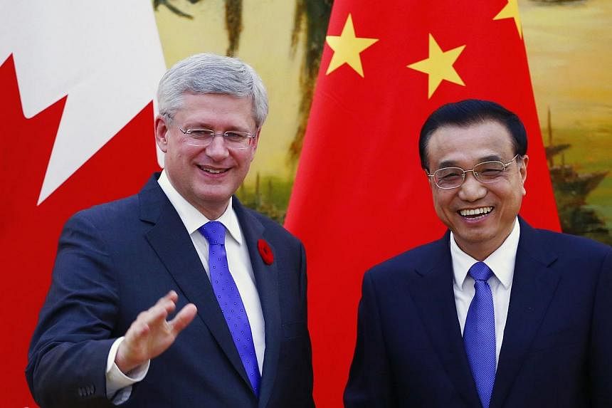 Canada's Prime Minister Stephen Harper (left) gestures next to China's Premier Li Keqiang, in front of Canadian and Chinese national flags, during a joint news conference at the Great Hall of the People in Beijing, China on Nov 8, 2014. -- PHOTO: REU