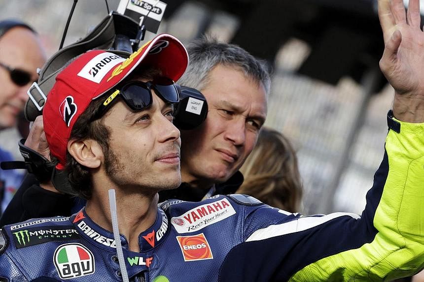 Yamaha MotoGP rider Valentino Rossi of Italy celebrates his pole position after the qualifying session of the Valencia Motorcycle Grand Prix at the Ricardo Tormo racetrack in Cheste, near Valencia, Spain on Nov 8, 2014. -- PHOTO: REUTERS