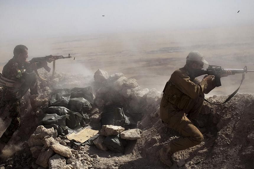 Iraqi fighters firing at Islamic-State (IS) militant positions. -- PHOTO: AFP