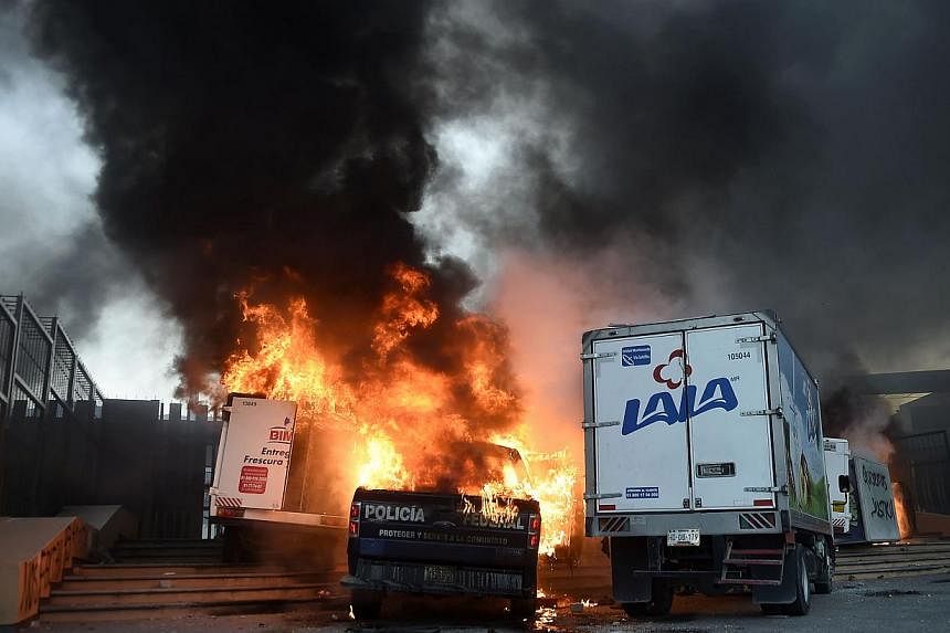 View of burning vehicles during a protest demanding for justice in the case of the 43 missing students, outside the State Government headquarters in Chilpancingo, Mexico, on Nov 8, 2014. -- PHOTO: AFP&nbsp;