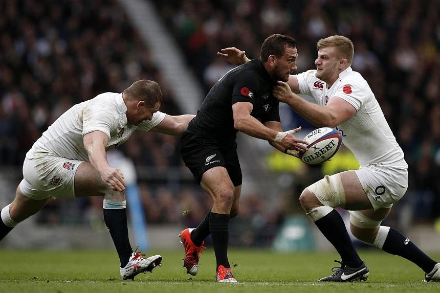 New Zealand's Aaron Cruden (centre) passes the ball as he gets tackled by England's Dylan Hartley (left) and George Kruis (right) during the Autumn international rugby union Test match between England and New Zealand at Twickenham Stadium on Nov 8, 2
