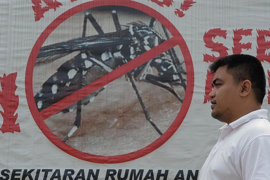 A man walks past a banner to promote the fight against dengue in Ampang, in the suburbs of Kuala Lumpur on Nov 5, 2014. -- PHOTO: AFP&nbsp;