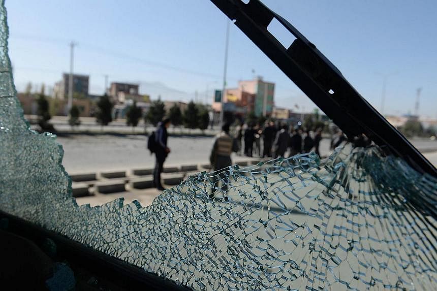 Afghan security forces are seen through the shattered glass of a bus at the scene of the roadside bomb blast in Kabul on Nov 10, 2014.&nbsp;Bombs exploded in three cities in Afghanistan on Monday killing at least 10 policemen, officials said, a day a